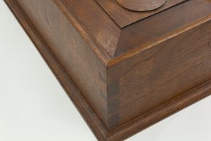 The corner of a document box with molded top edge that's mitered above its dovetails.