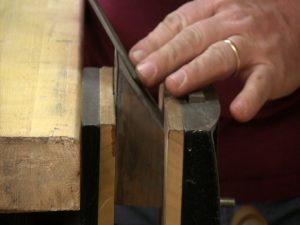 To sharpen the cabinet scraper, use a 45° block to guide the file.